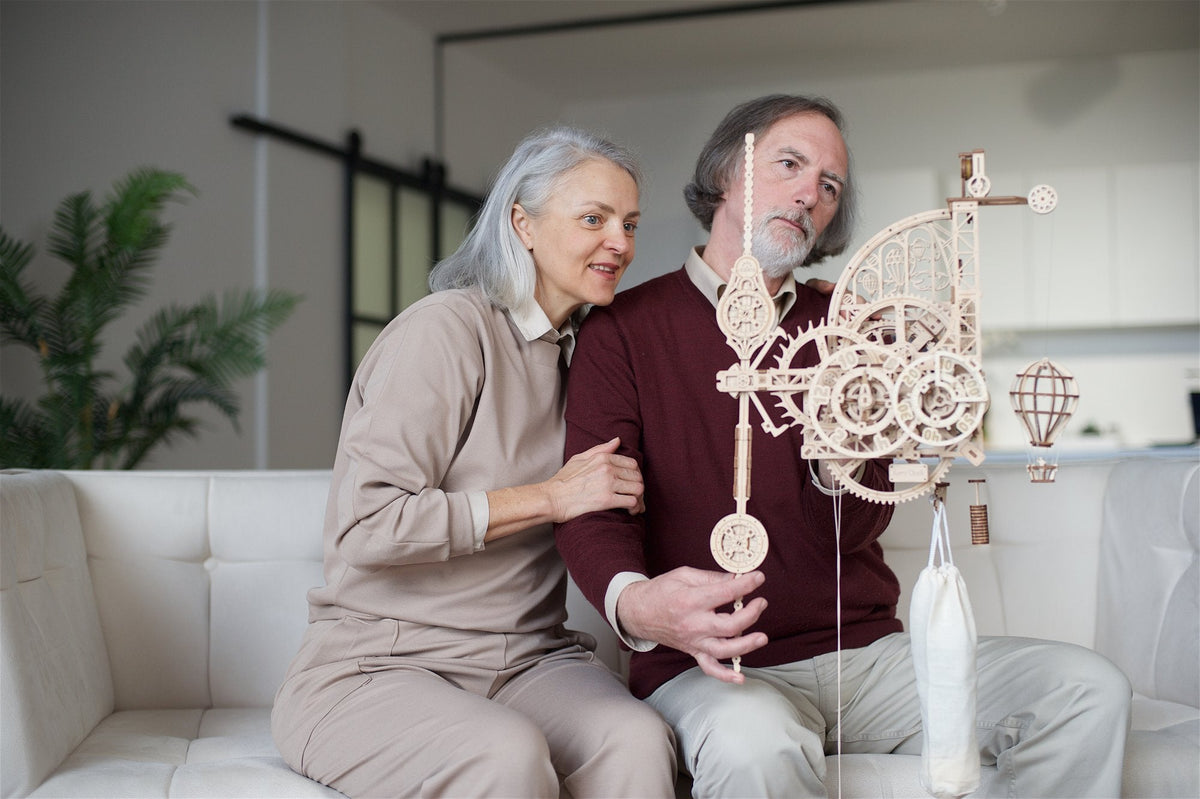 Two people on a sofa with the finished wooden Aero clock