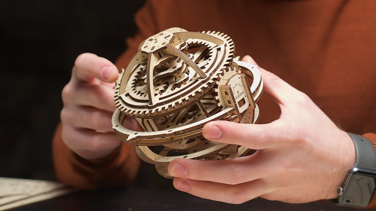Zwei Hände halten das fertig gebaute Tourbillon der Holzuhr Sternengucker