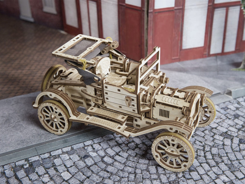 Retro-Auto UGR-T aus Holz auf Kopfsteinpflaster vor einer Häuserzeile