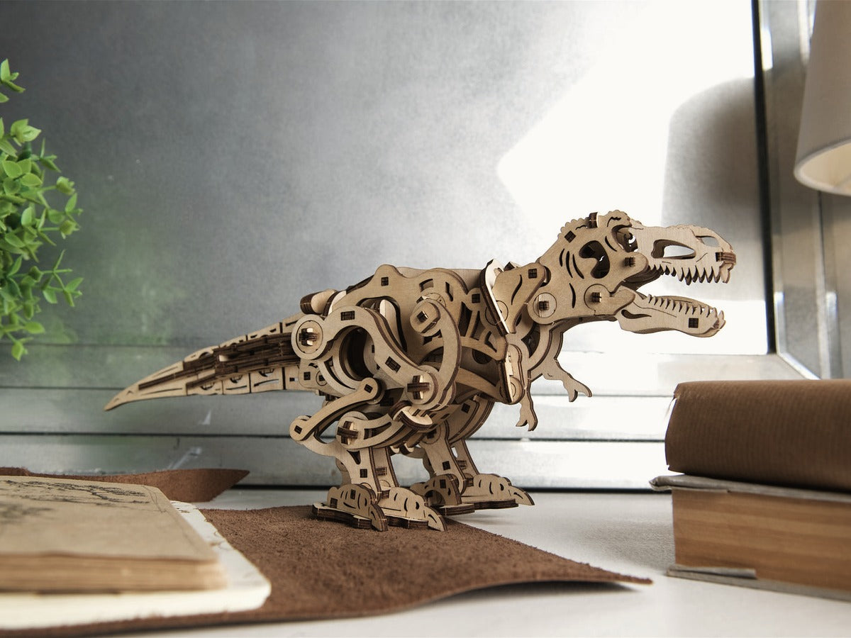 Tyrannosaurus Rex aus Holz auf einem Schreibtisch neben Buch und Pflanze
