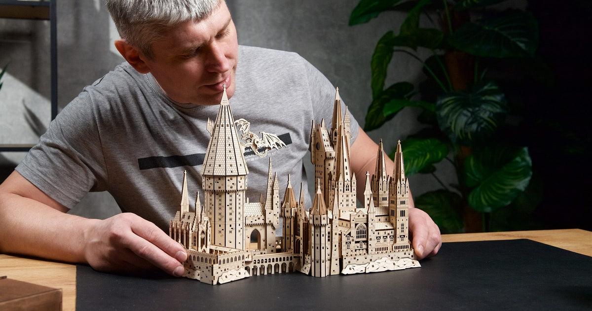 Person baut das Modell von Schloss Hogwarts aus lasergeschnittenen Holzteilen zusammen