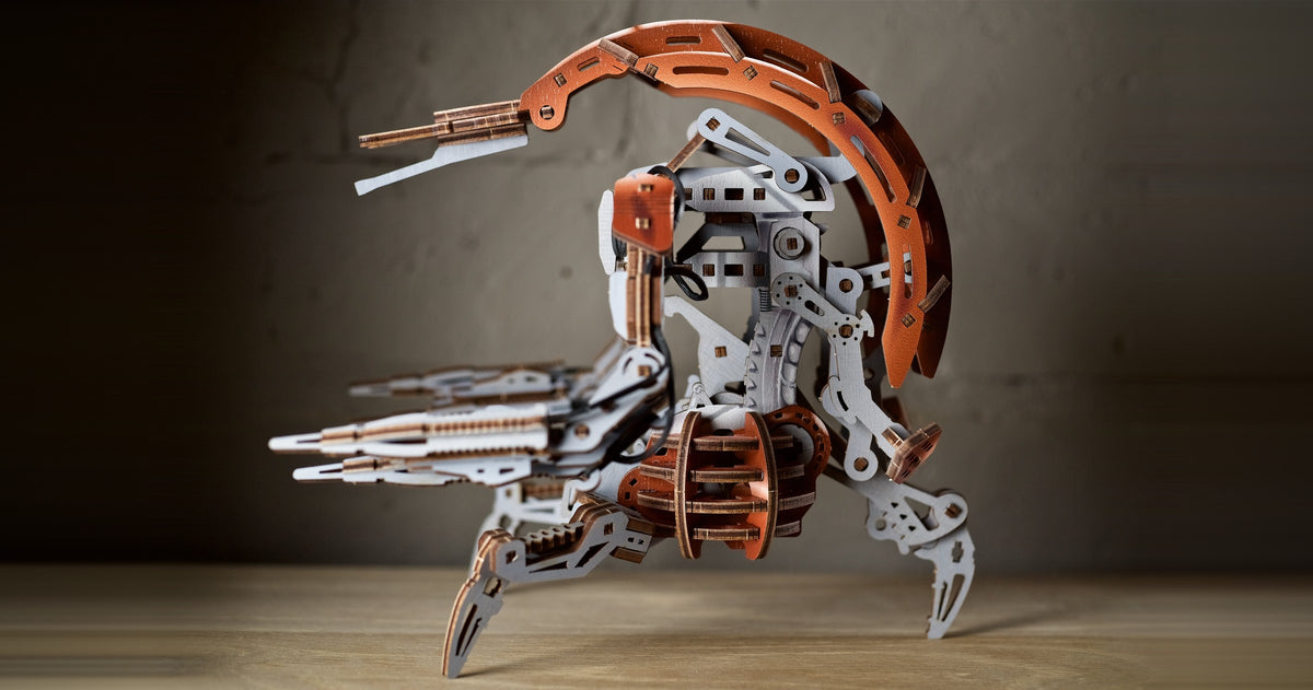 Holzmodell des Droideka aus lasergeschnittenem Sperrholz auf einem Holztisch vor einer Betonwand