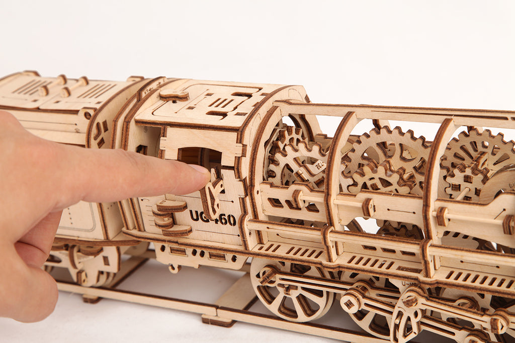 Finger pointing at the gear train of the wooden steam locomotive