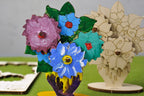 Blumenstrauß aus Holz, bunt bemalt neben unbemalter Version