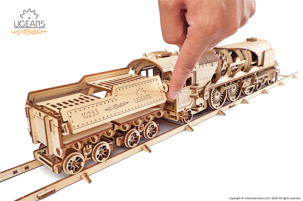 Hand schiebt die V-Express Dampflokomotive mit Tender aus Holz auf Schienen