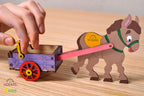 Hand bewegt den bemalten Esel mit Karren aus Holz